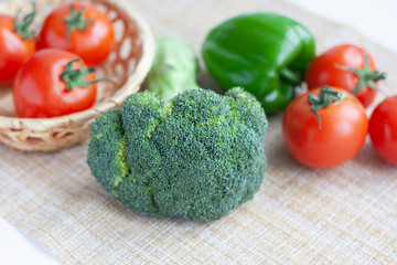 Ripe broccoli, green bell peppers and tomatoes in a basket and pepper shaker