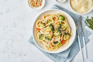 Spaghetti pasta with broccoli, bucatini with peppers, garlic, pine nuts. Top view, copy space