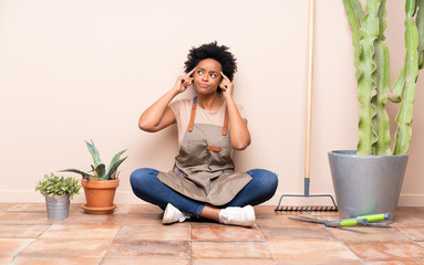 Gardener woman sitting on the floor having doubts and thinking