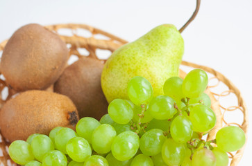 Ripe kiwi, pear and grapes in a wicker basket