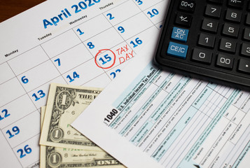 April 15 National Tax Day calendar, money tax return form and calculator on the table