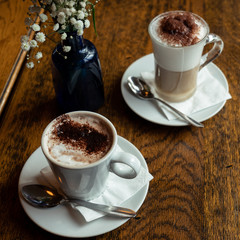 Hot chocolate and capuchino served on a wooden table.