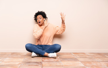 African american woman sitting on the floor nervous and scared