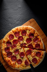 Pepperoni Pizza with Mozzarella cheese, salami, Tomato sauce, pepper, Spices. Italian pizza on Dark grey black slate background