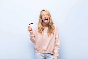young blonde woman with cheerful, carefree, rebellious attitude, joking and sticking tongue out,...