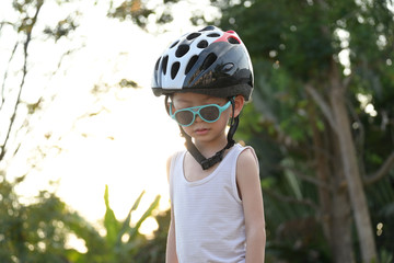 cute child wear sunglasses and sport helmet playing bicycle exercise in the morning day