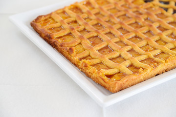 Homemade rustic style tart with apricot jam. Italian dessert. White background and copyspace