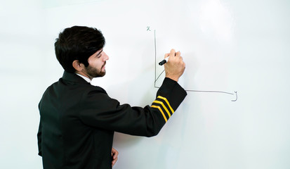 Young pilot man in uniform writing graph by marker on whiteboard having discussion with business...