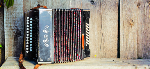 Old lonely accordion on the bench in summer sunny weather. Panorama.	