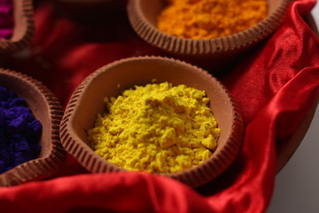 Variety of Holi colors placed in earthen platter with white background (Holi Concept)