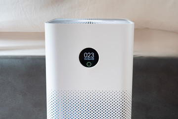 Indoor air purifier with digital monitor screen in bedroom, that show air quality in the room and air pollution levels in the room. PM 2.5 is a major environmental health problem affecting everyone.