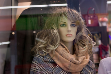 Fototapeta na wymiar female mannequin with long blond hair in a checkered coat, with a scarf shawl on the neck