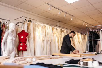 Couple of fashion designers working with fabric and clothing sketches at the studio full of...
