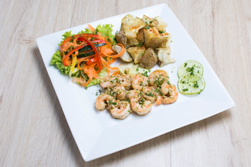 Garlic shrimp, bathed in garlic sauce, accompanied by potatoes and vegetables