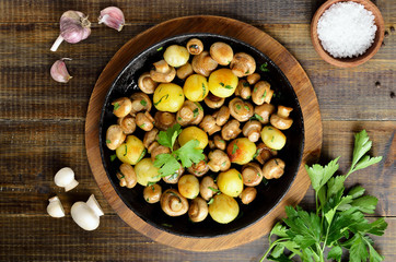 Fototapeta na wymiar Delicious fried mushrooms with potatoes in cast iron pan
