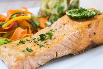 Salmon with garlic and lemon, accompanied by sauteed vegetables and spicy potatoes