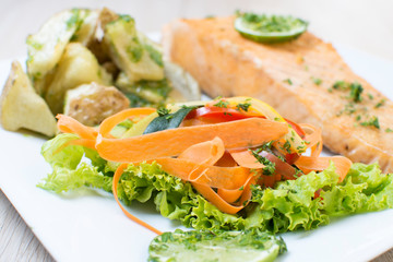 Salmon with garlic and lemon, accompanied by sauteed vegetables and spicy potatoes