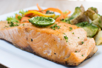 Salmon with garlic and lemon, accompanied by sauteed vegetables and spicy potatoes