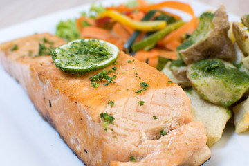 Salmon with garlic and lemon, accompanied by sauteed vegetables and spicy potatoes