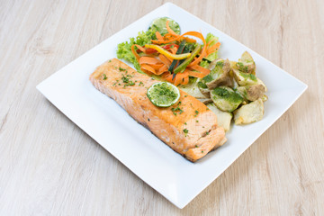 Salmon with garlic and lemon, accompanied by sauteed vegetables and spicy potatoes