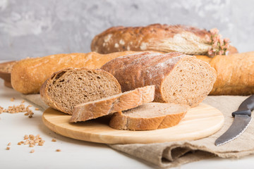 Sliced bread with different kinds of fresh baked bread on a white wooden background. side view, selective focus.