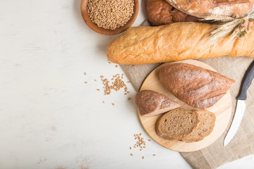 Sliced bread with different kinds of fresh baked bread on a white wooden background. top view, copy space.