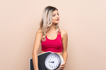 Teenager sport girl over isolated background with weighing machine