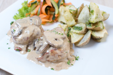 Pork tenderloin in mushroom sauce, accompanied by spicy potatoes and vegetables