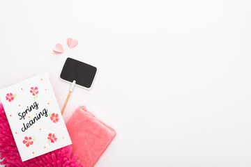 top view of pink cleaning supplies, hearts and empty sign near spring cleaning card on white background