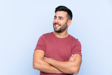 Obraz premium Young handsome man with beard over isolated blue background happy and smiling