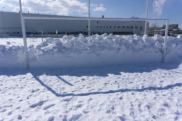 Old abandoned wooden soccer goal covered with snow during winter season .
