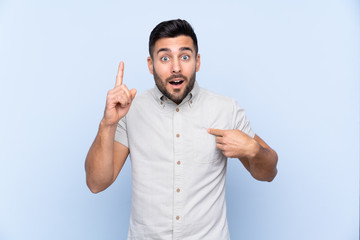 Young handsome man with beard over isolated blue background with surprise facial expression