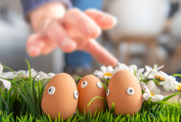 Clogged Easter eggs are found during the Easter breakfast at the kitchen table, the eggs are caught by a boys hand. Happy Easter concept, Easter theme, background, postcard, screen, greeting card,