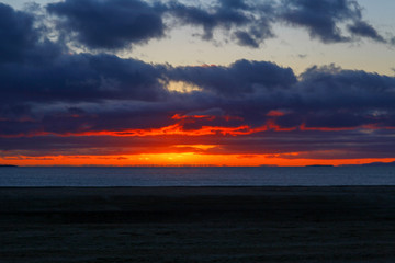 Beautiful sunset over the ocean with waves moving to shore on the North Shore of Iceland.