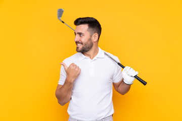 Golfer player man over isolated yellow background pointing to the side to present a product