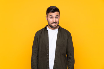 Man over isolated yellow background having doubts and with confuse face expression