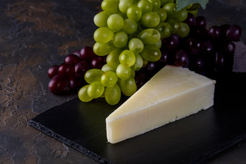 Pecorino romano, hard italian sheep milk cheese on black stone board, selective focus