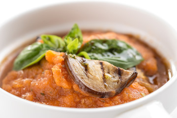 Squash zucchini or pumpkin paste puree with grilled eggplant and basil in white bowl isolated on white background