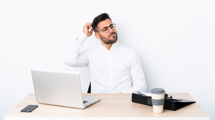 Young businessman in a workplace having doubts while scratching head