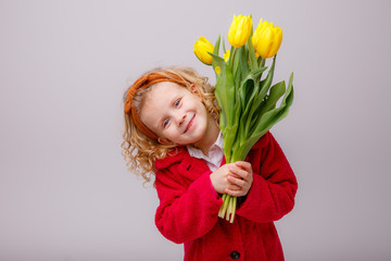 a child little  girl holding a bouquet of yellow tulips on a white background