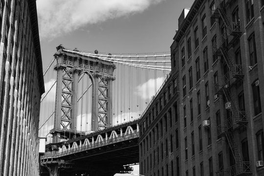 Black and White Photo of the Manhattan Bridge between Old Brick Buildings in Dumbo Brooklyn New York
