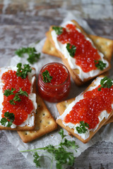 Crackers with red caviar and cream cheese. Jar with red caviar. Omega 3 product.
