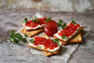 Crackers with red caviar and cream cheese. Jar with red caviar. Omega 3 product.