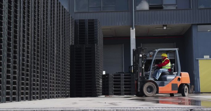 Warehouse worker driving forklift outside factory