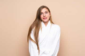Obraz premium Teenager girl in a bathrobe over isolated background having doubts and with confuse face expression