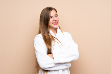 Teenager girl in a bathrobe over isolated background looking to the side