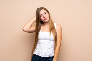 Teenager blonde girl over isolated background having doubts while scratching head