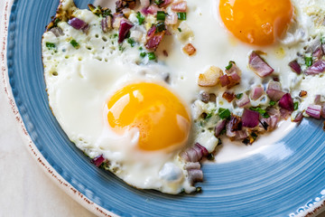 Sunny Side Up Fried Eggs with Red Onions and Chives for Breakfast in Plate.