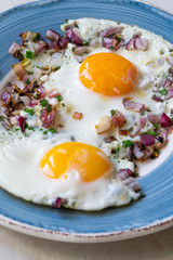 Sunny Side Up Fried Eggs with Red Onions and Chives for Breakfast in Plate.