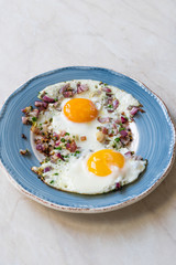 Sunny Side Up Fried Eggs with Red Onions and Chives for Breakfast in Plate.